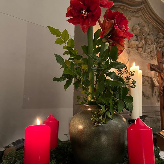 Adventskranz mit roten Kerzen und Blumen